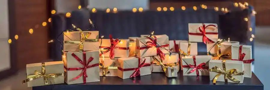 一堆礼物包裹在工艺纸上,上面有红色和金色的丝带,放在黑色的木桌上