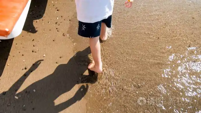 小男孩脚在沙滩上行走的特写图片