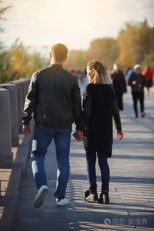 年轻夫妇男孩和女孩在秋天公园散步堕落外面的年轻人和女人幸福的家庭