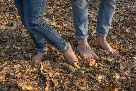 赤脚的沉淀物向森林地面.无鞋的人照片