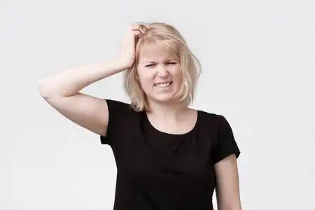 美丽的年轻金发碧眼的女人抓头照片