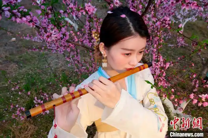 一位女子在桃花下吹笛. 王成前 摄