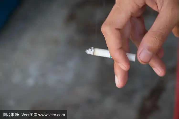 一个男人站着抽烟,手里拿着一支香烟的形象