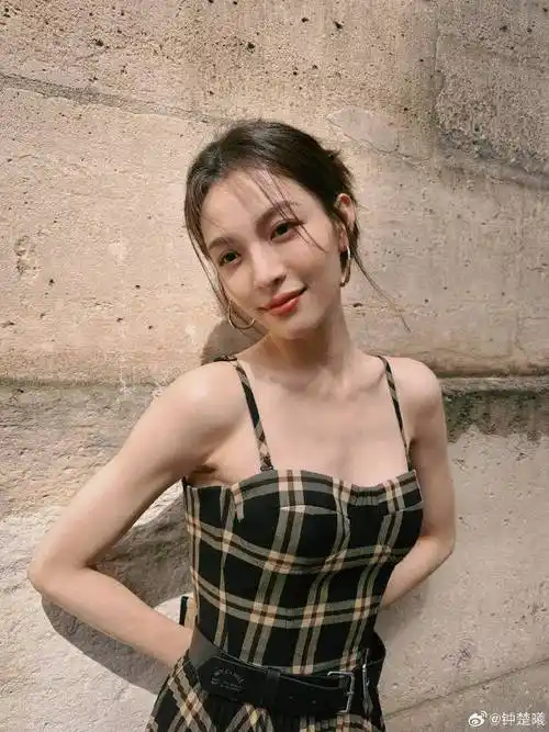 钟楚曦穿着吊带裙,她侧身拿着名贵小包挡住胸部,那风情万种的妩媚劲儿