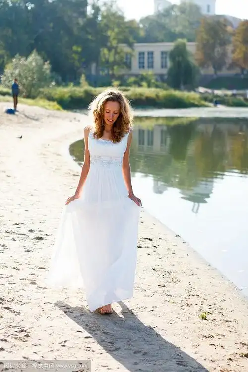 年轻的女孩新娘赤脚走在阳光明媚的河岸