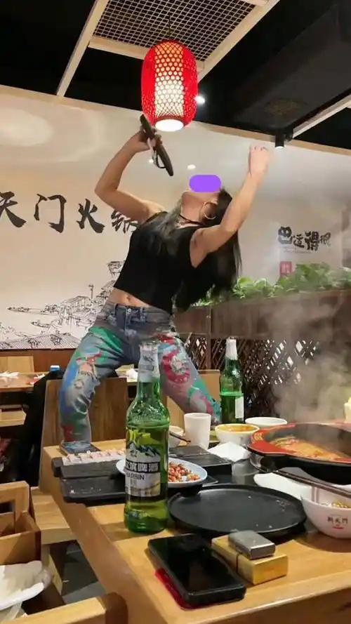 一女子喝醉酒,站在餐饮店的椅子上,拿拖鞋当话筒唱歌