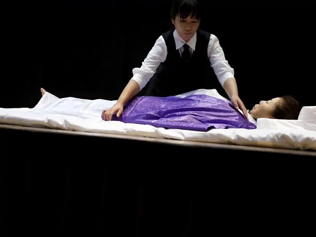 入殓师为死者擦拭身体,进行处理,穿好寿衣,按照生前的形容画好妆,这一