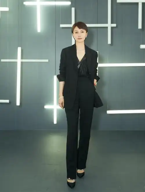袁泉身穿一条黑色西服,内搭黑色条纹深v打底衫,脚上一双黑色高跟鞋,一