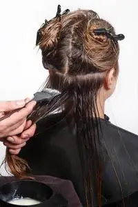 发型师用刷子在客户的头发上敷面膜照片