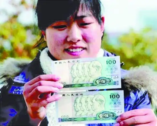 农场的但先生将其收藏的两张面值相同且同号的100元人民币展示给记者