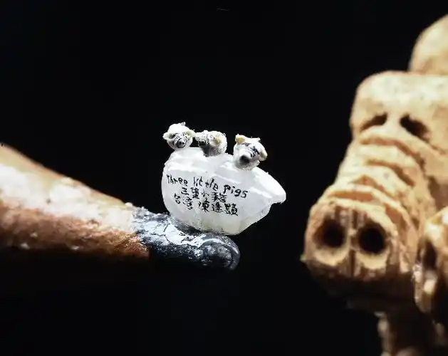 微雕作品"三只小猪"中的每只小猪长宽高均约1毫米,它们并排"站"在一颗