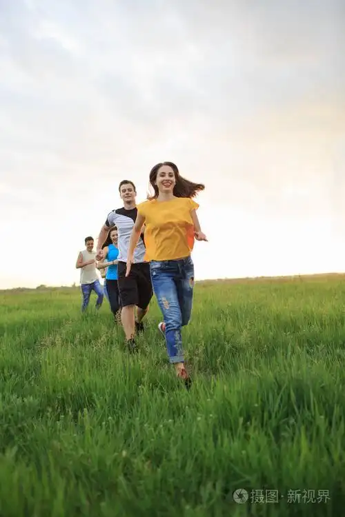 一群人在草地上奔跑, 年轻人围着田野奔跑.