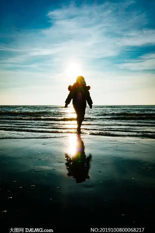 蓝天下在海边散步的人物剪影摄影图片