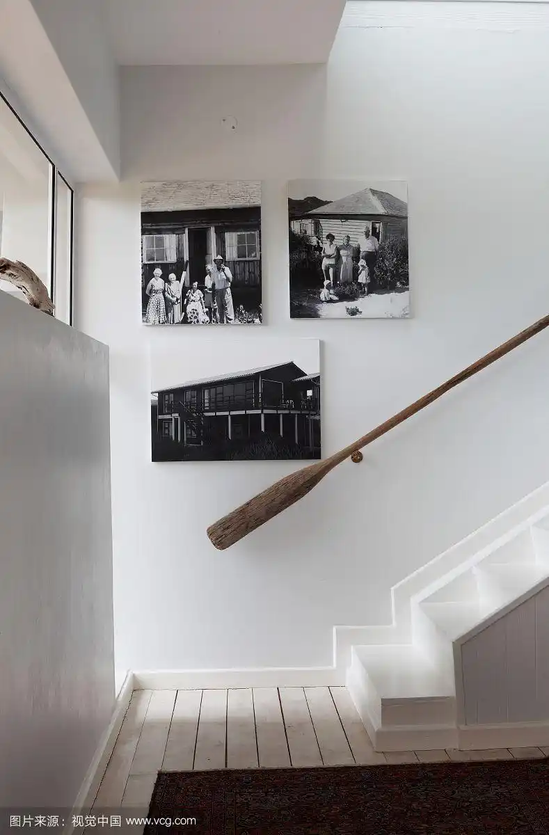 楼梯间有老式的木制扶手,墙上挂着黑白照片