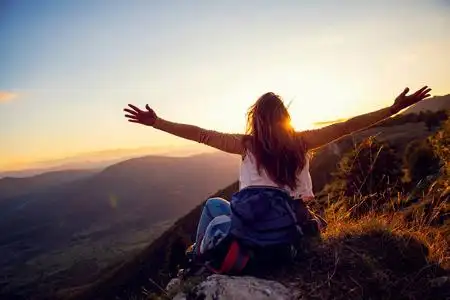 山顶夕阳年轻女子举手站在山顶和夕阳天空抽象的背景上.照片