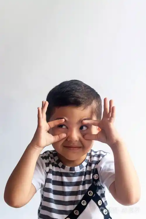 灰色背景下天真微笑的小男孩.小男孩扭伤了脸.人,童年生活方式的概念.