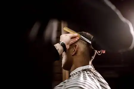 理发师在理发店为一个时髦的黑发男人剪发.男式时尚照片