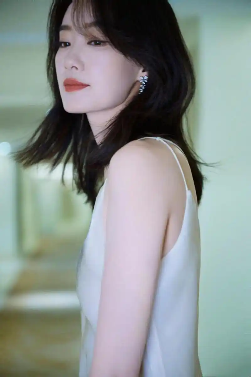 7月22日,张小斐分享阳光下写真照,照片中,张小斐身穿白色丝绸吊带长裙