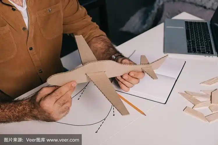 男人抱着纸板飞机模型在家建模裁剪的镜头