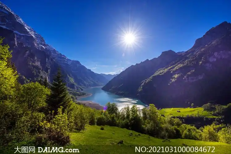 阳光下的山谷湖泊和草地摄影图片