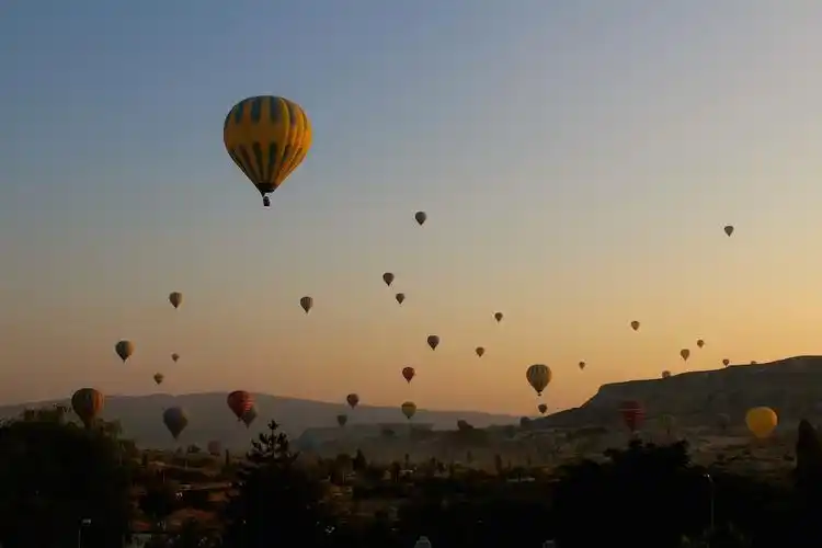 the sky is lightening up, and balloons in the distance are in