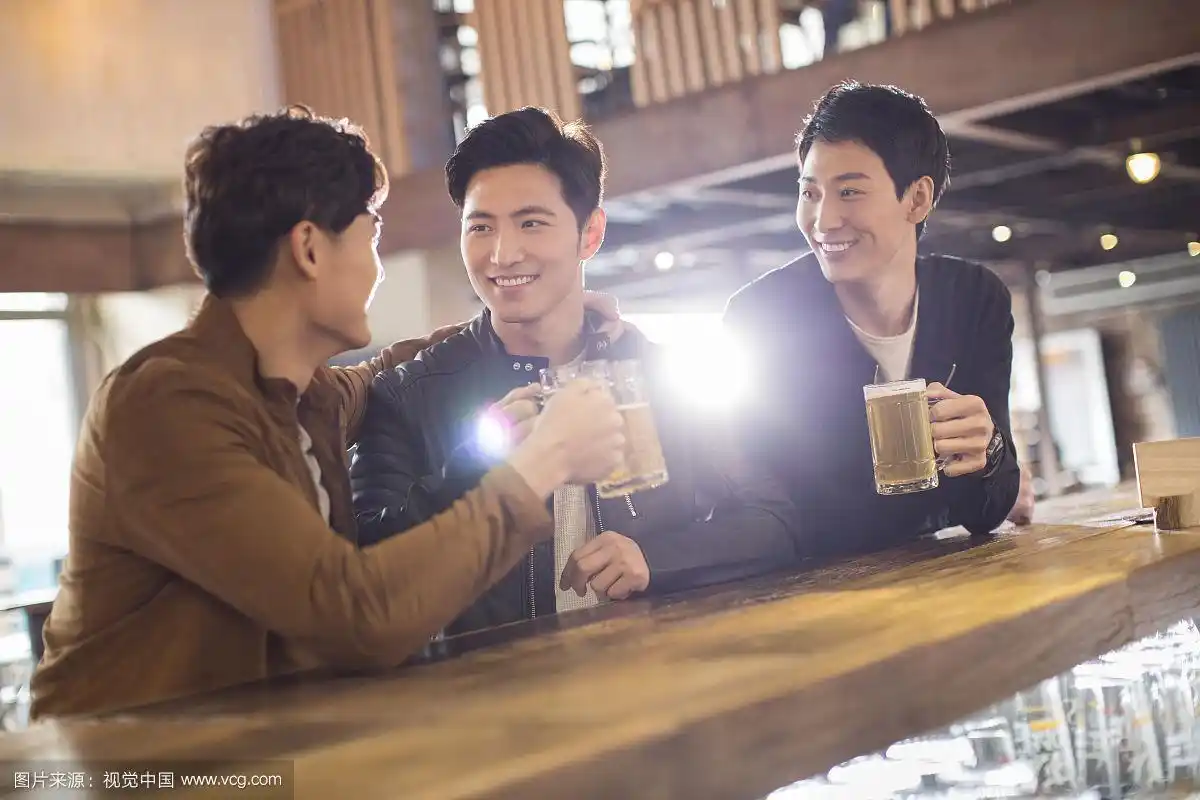 快乐的年轻男士在酒吧喝酒