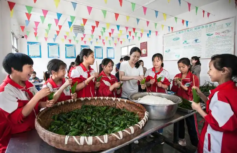 2021年6月11日,贵州省黔西市洪水镇平桥小学,老师教学生包粽子.