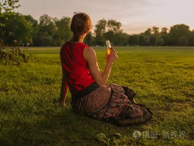喝酒的女人在公园里欣赏日落