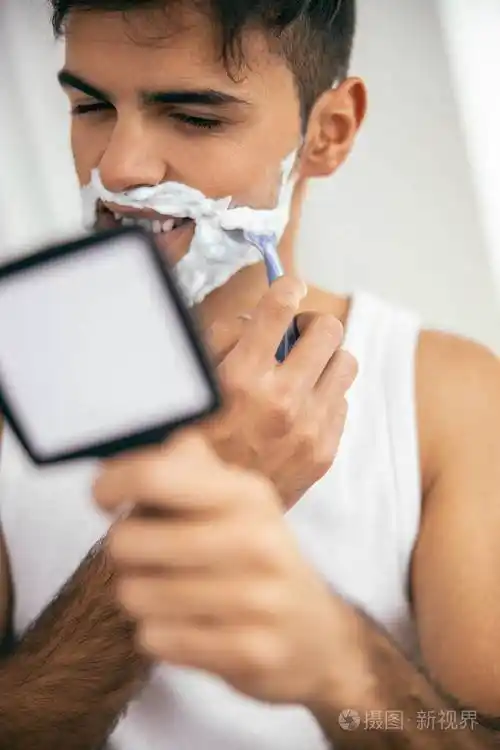 穿着白色t恤的快乐男人刮胡子