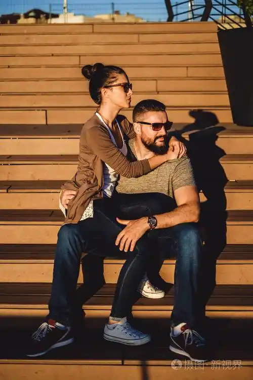 女朋友坐在她的男朋友膝上在一个晴朗的天