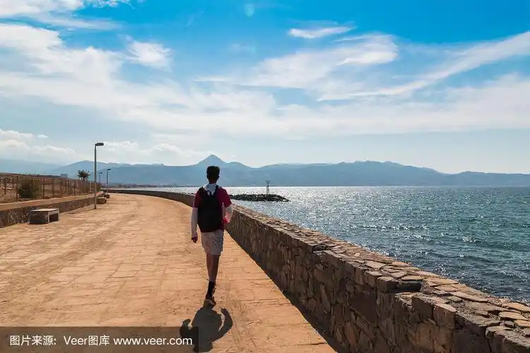 一个年轻人在阳光下的海边散步