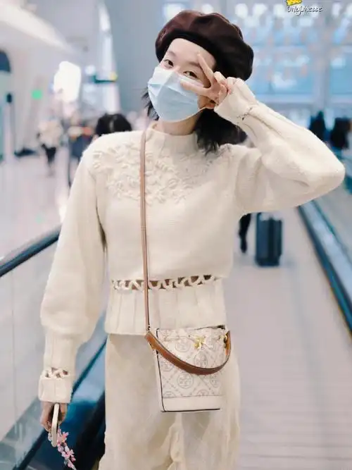 乔欣机场私服look,身穿镂空毛衫搭配不规则褶裙,整体都是淡色系,搭配