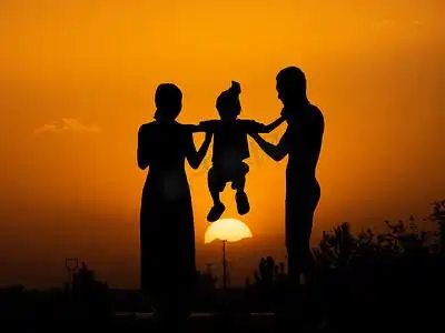 人像剪影夕阳一家三口夕阳下父母抬起孩子摄影图配图