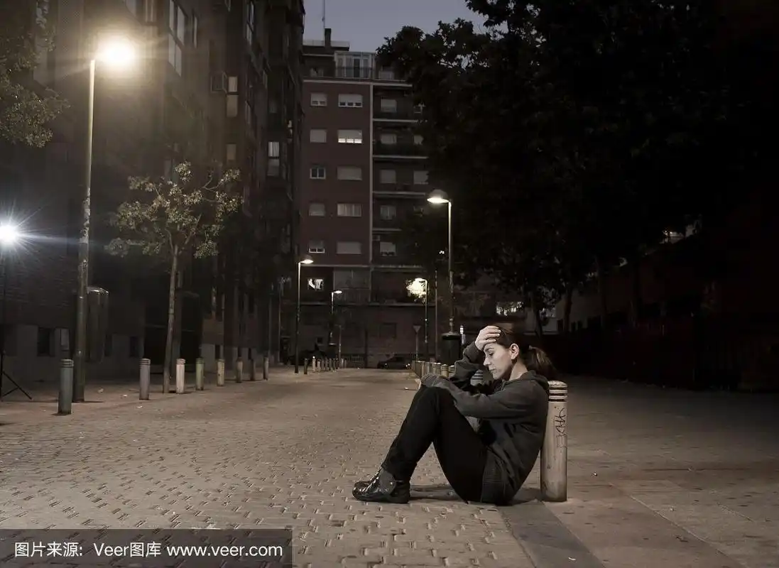 悲伤的女人晚上独自坐在街边沮丧