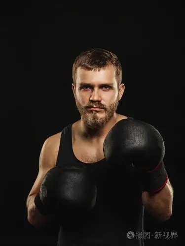 戴着手套在深色背景上的竞技胡子的拳击手