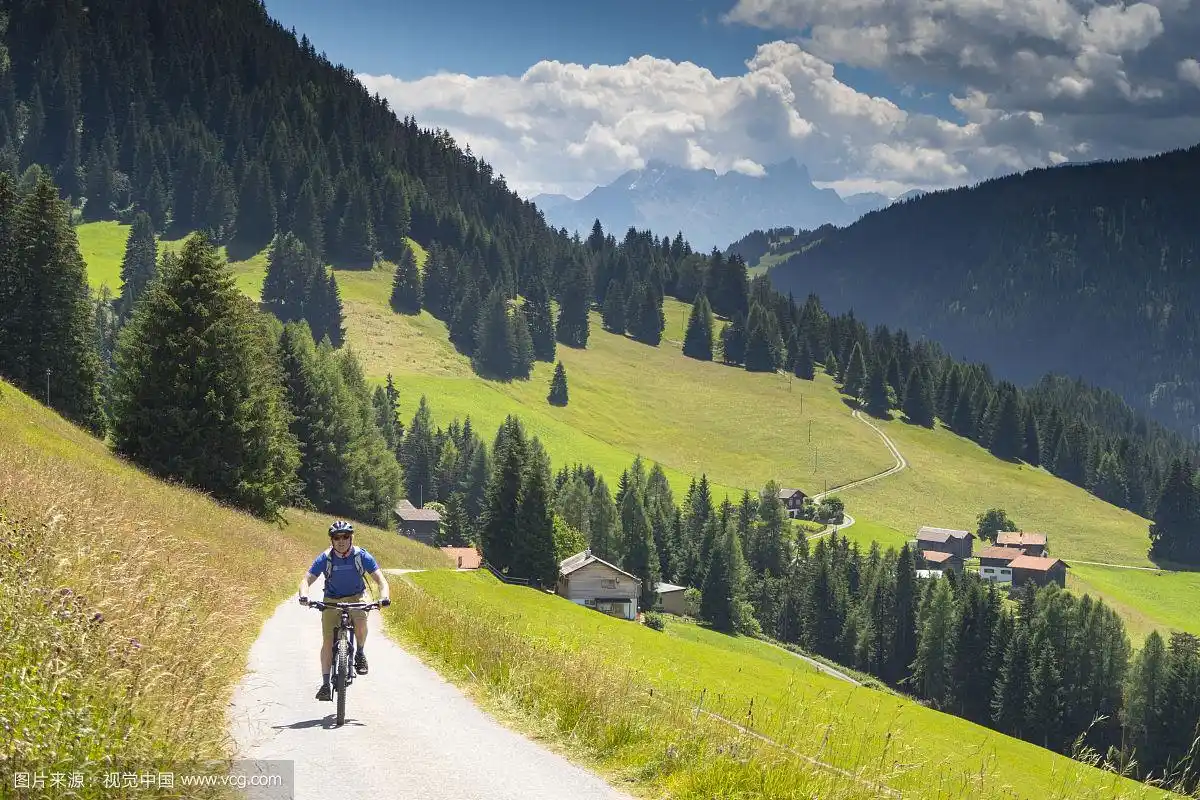 男人骑山地车在土路与高山草甸的背景