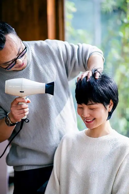 丈夫用电吹风吹干妻子的头发图片下载