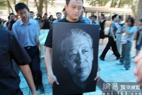 文兴宇的儿子手捧遗像引领棺木.