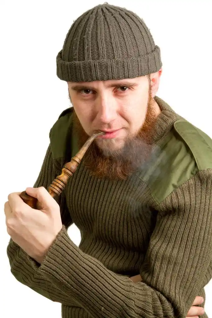 年轻大胡子的男人抽着烟斗