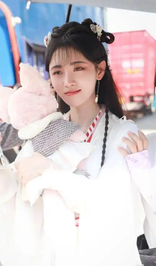 背后还有工作人员给撑着伞,可以说待遇是很好了,照片里鞠婧祎一直抱着