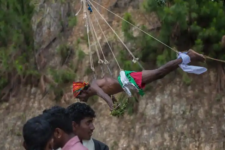 在木棒的前端用绳子和大多个铁钩穿过人体的皮肤悬挂着一个教徒,这