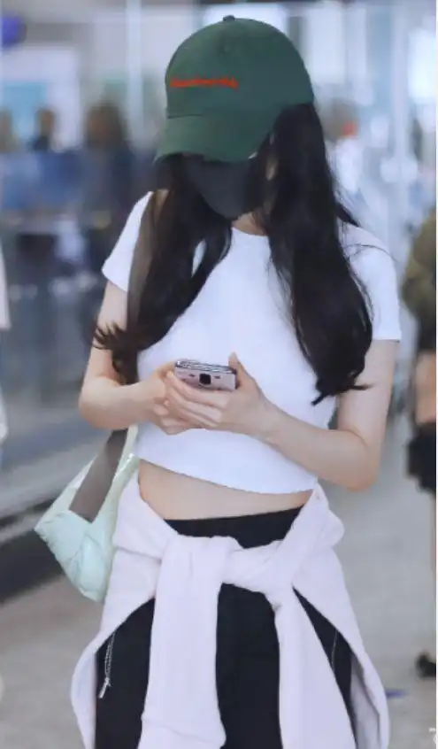 杨幂露脐装现身机场白衣绿帽勾勒好身材网友却说肥肉出来了