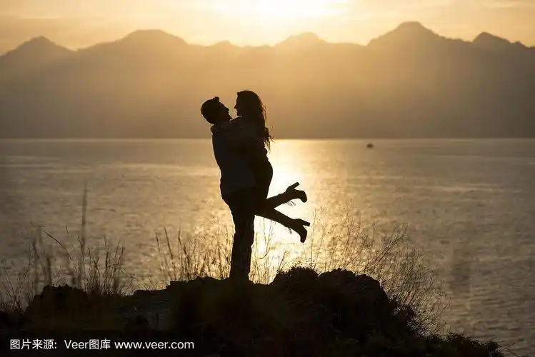 日落时分,一对情侣在海边的悬崖上拥抱