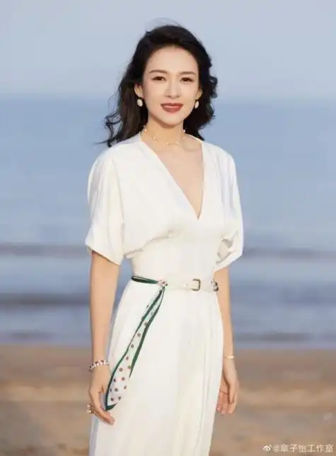 章子怡身穿白色深v套装显精致,笑容灿烂,海风吹拂长发,气质优雅出众