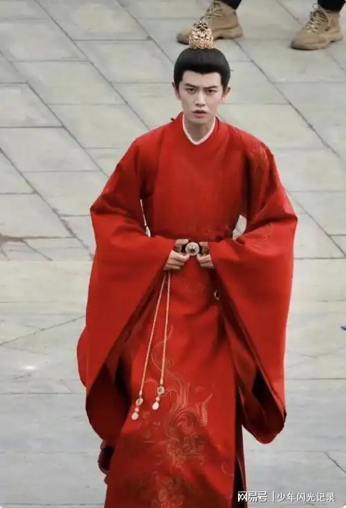 这张照片中,任嘉伦身穿一件华丽的红色官服,深色的外衣配上金色的铜钱