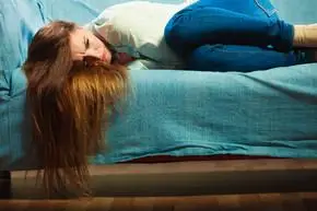 孤独的负面情绪概念.年轻悲伤的压力大的女人躺在家里的沙发上