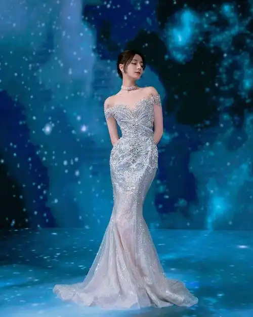 身后这片满是星空的背景墙,与迪丽热巴身上的银色流光鱼尾裙完美融合