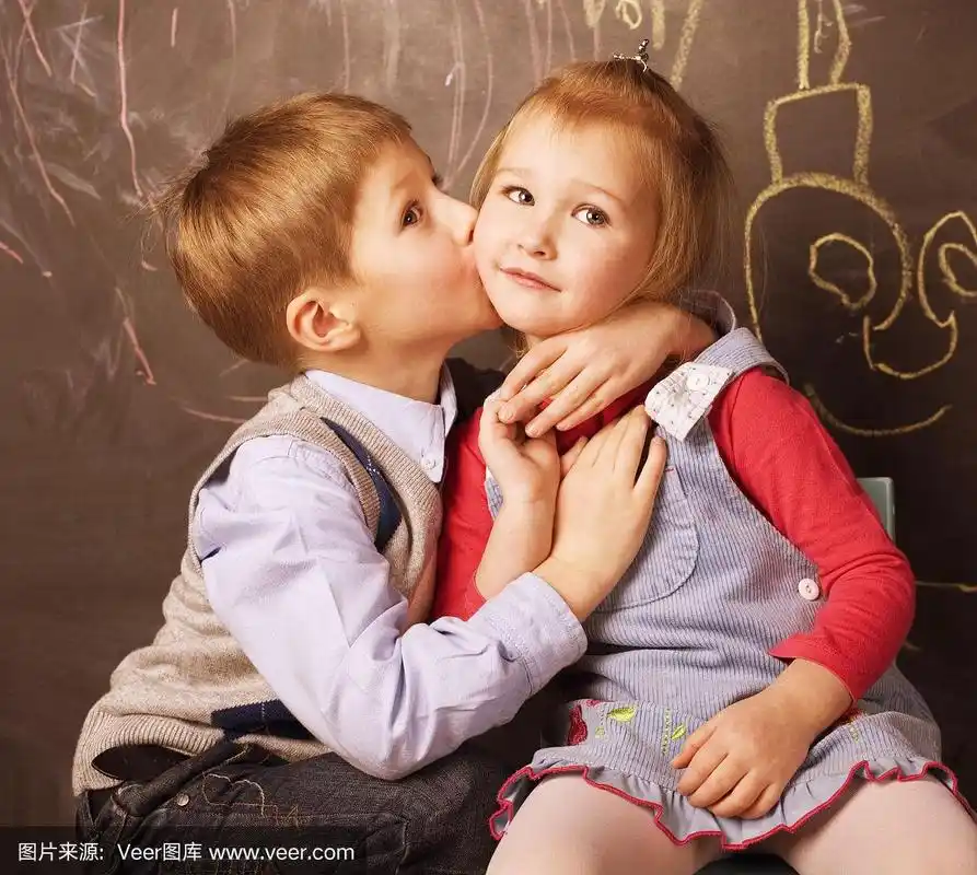 可爱的小男孩在教室里亲吻女孩