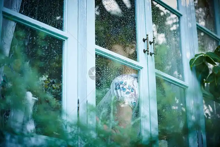 下雨天靠在窗边发呆的女性