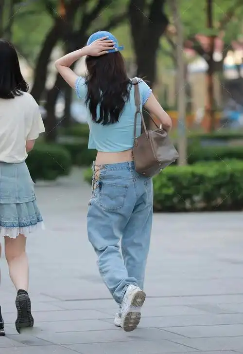 宽松版型的牛仔裤搭配短款上衣营造出潮流时尚的感觉